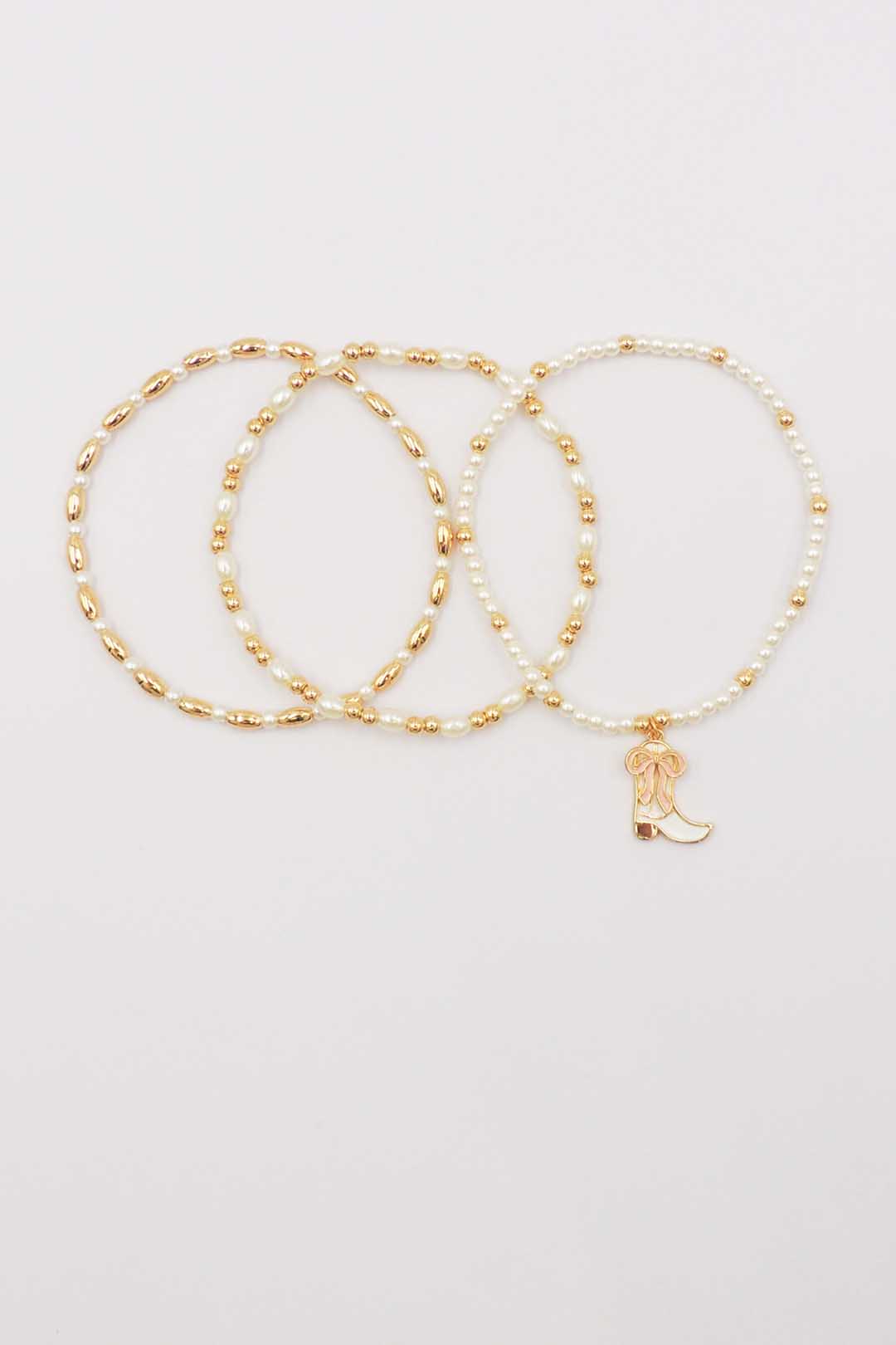 Set of Three Gold and Pearl Stretch Bracelets with Light Pink Bow on White Cowboy Boot Charm
